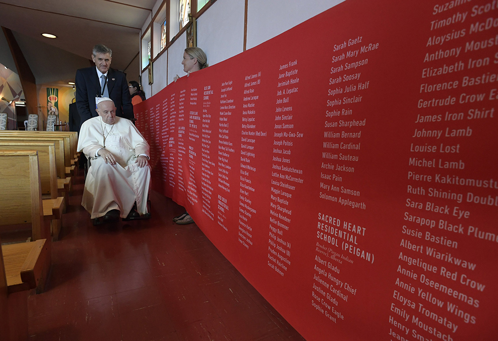 Pope Francis prays in front of a banner bearing the names of each of the 4,120 Indigenous children and the residential school where they died, in this photo from his visit to in Maskwacis, Alberta, July 25, 2022. (CNS photo / Vatican Media)