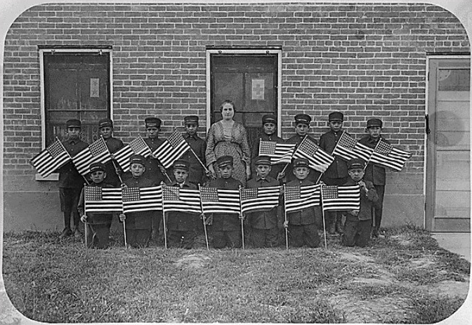 A very early class of young boys with flags at the Albuquerque Indian School. National Archives, Denver, Colorado, Identifier 292873