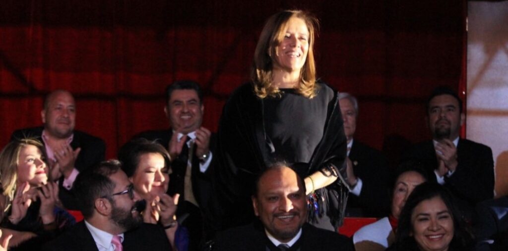 Standing, the former First Lady of Mexico, Margarita Zavala, is cheered by the crowd attending Naasón Joaquín García's celebration as leader of the Luz del Mundo Church. Behind her, Enrique Alfaro, then-governor of Jalisco and Naasón are seen clapping. December 14, 2018. Movimiento Ciudadano social media @ www.flickr.com/photos/dipciudadanos/45418829085/in/photostream/