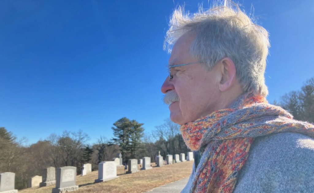 Terry McKiernan, president of BishopAccountability.org, visits a cemetery in Douglas where Phil Saviano is buried. Saviano was a board member of BishopAccountability.org and a survivor of child sex abuse by clergy in the Worcester Diocese. - Nancy Eve Cohen/NEPM